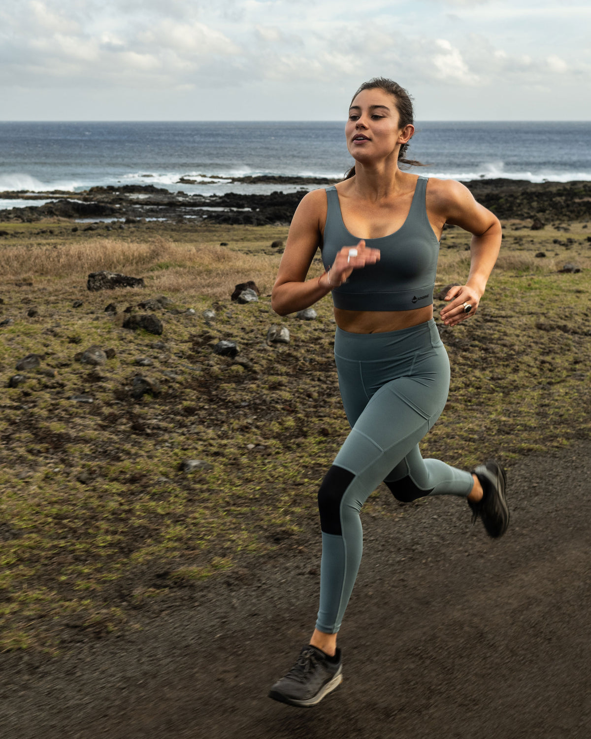 Woman running outdoors in performance activewear beside the coast